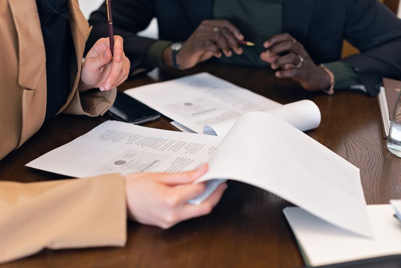 Two colleagues reviewing paperwork, close-up hands